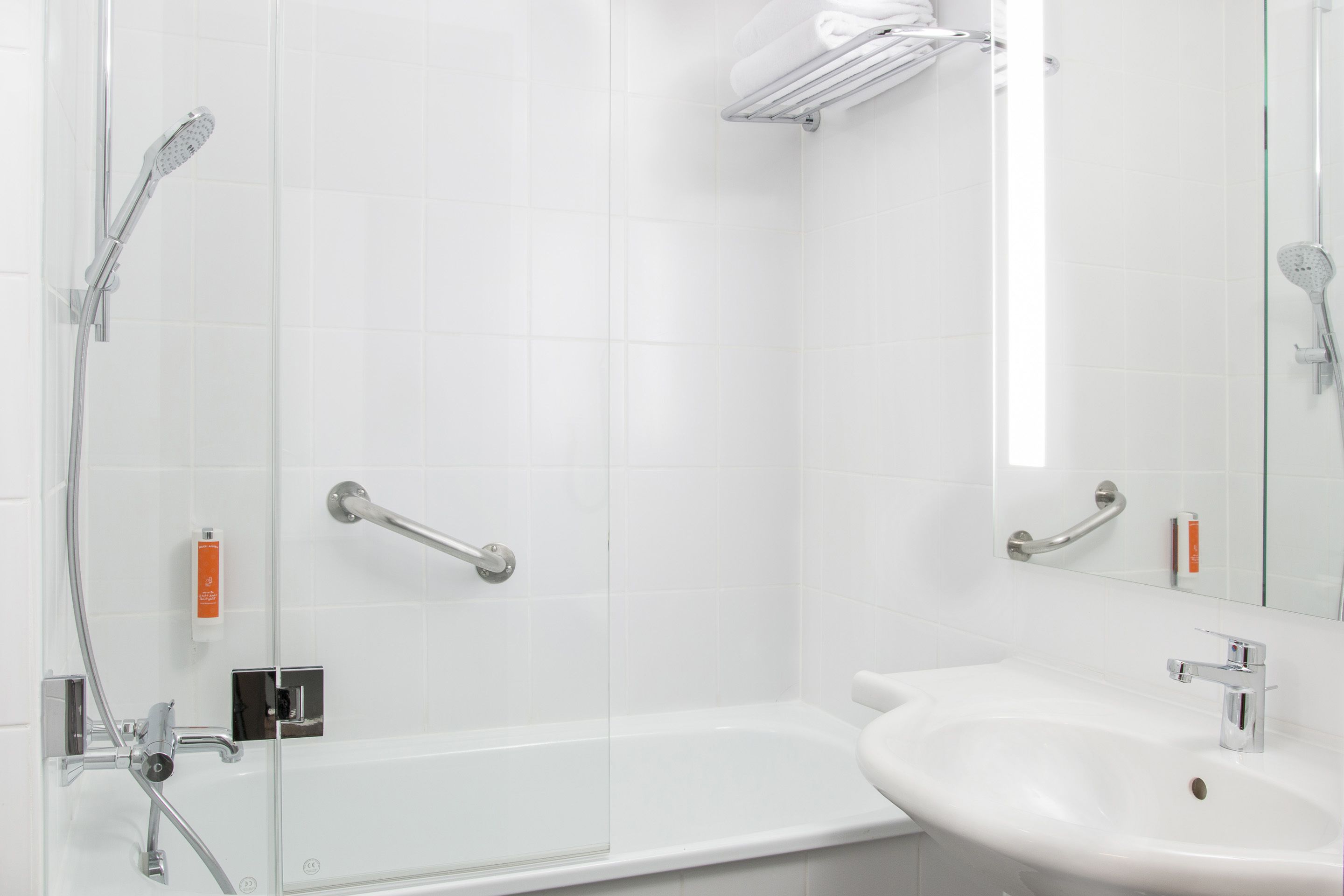 Un baño moderno con cabina de ducha de vidrio, un lavamanos blanco y bañera con mampara de vidrio.