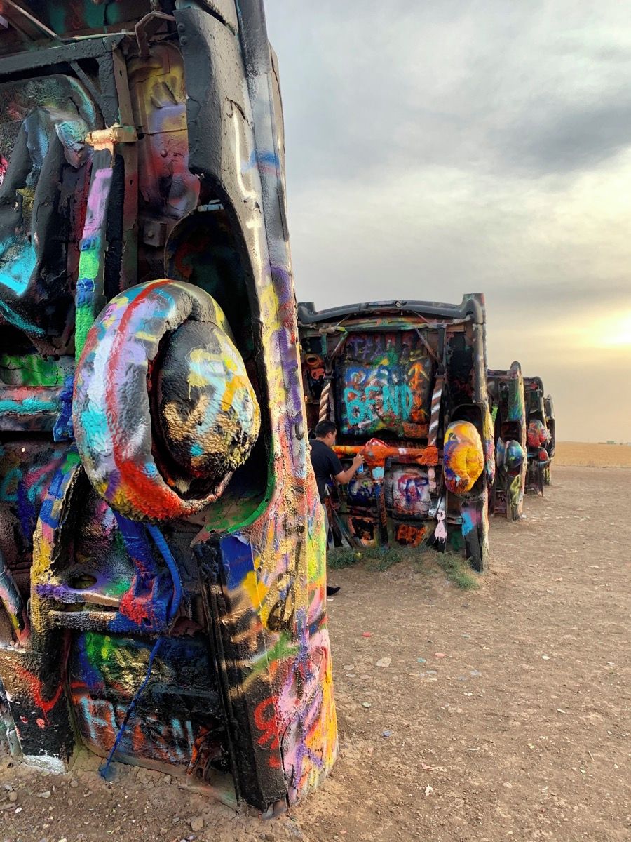 A row of abandoned vehicles covered in colorful graffiti.