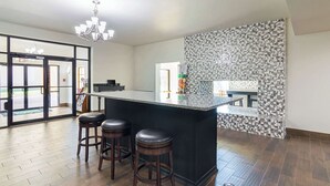A modern kitchen with a large island, two stools, and a patterned backsplash. - Quality Inn Amarillo East (Amarillo)
