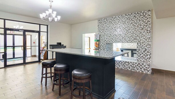 Une cuisine moderne dotée d’un grand îlot central, de deux tabourets et d’un crédence décorée.