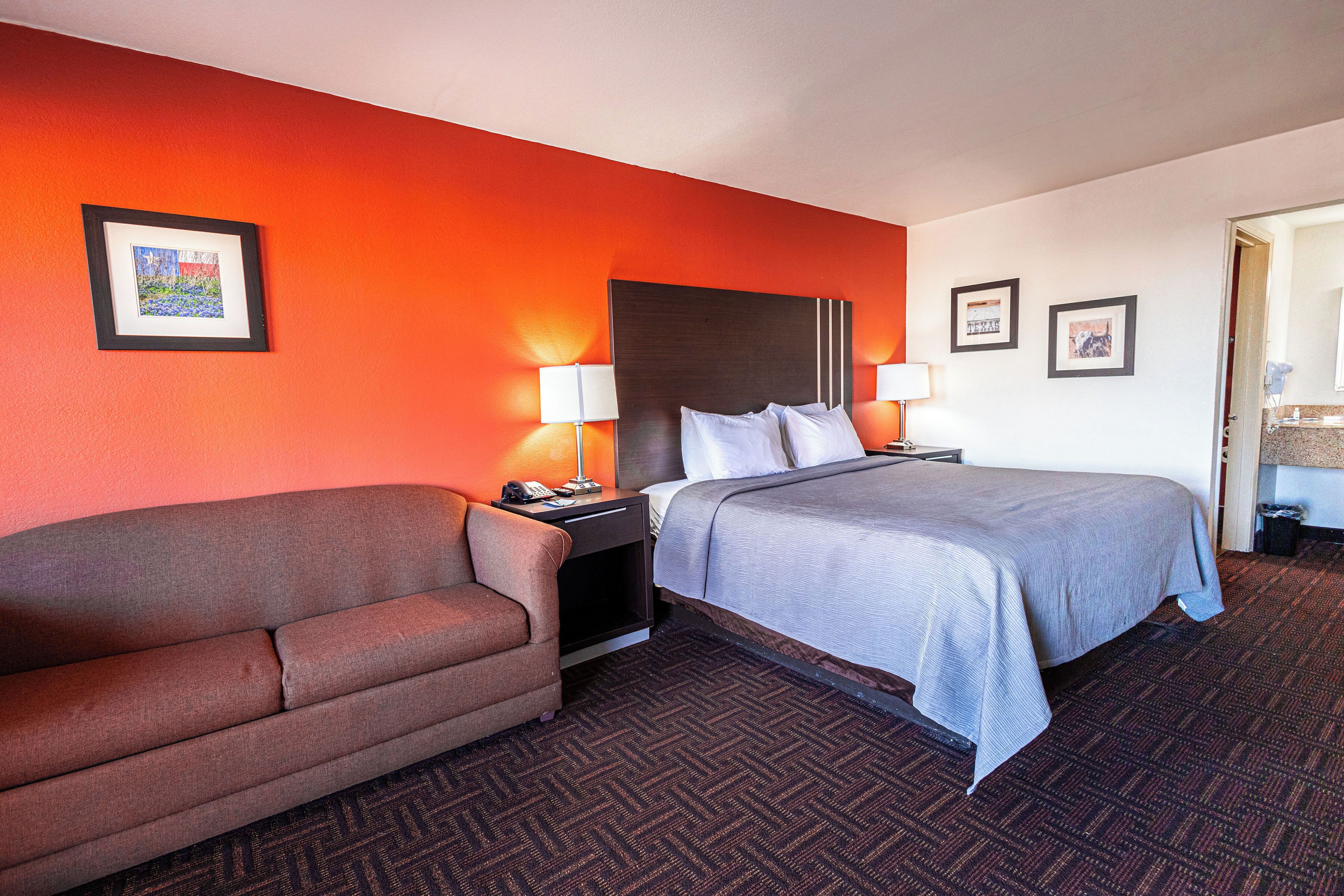 A hotel room with a bed, a sofa, and a nightstand with lamps.