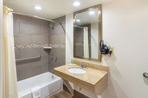 A bathroom with a bathtub, a sink, a shower, and a mirror.