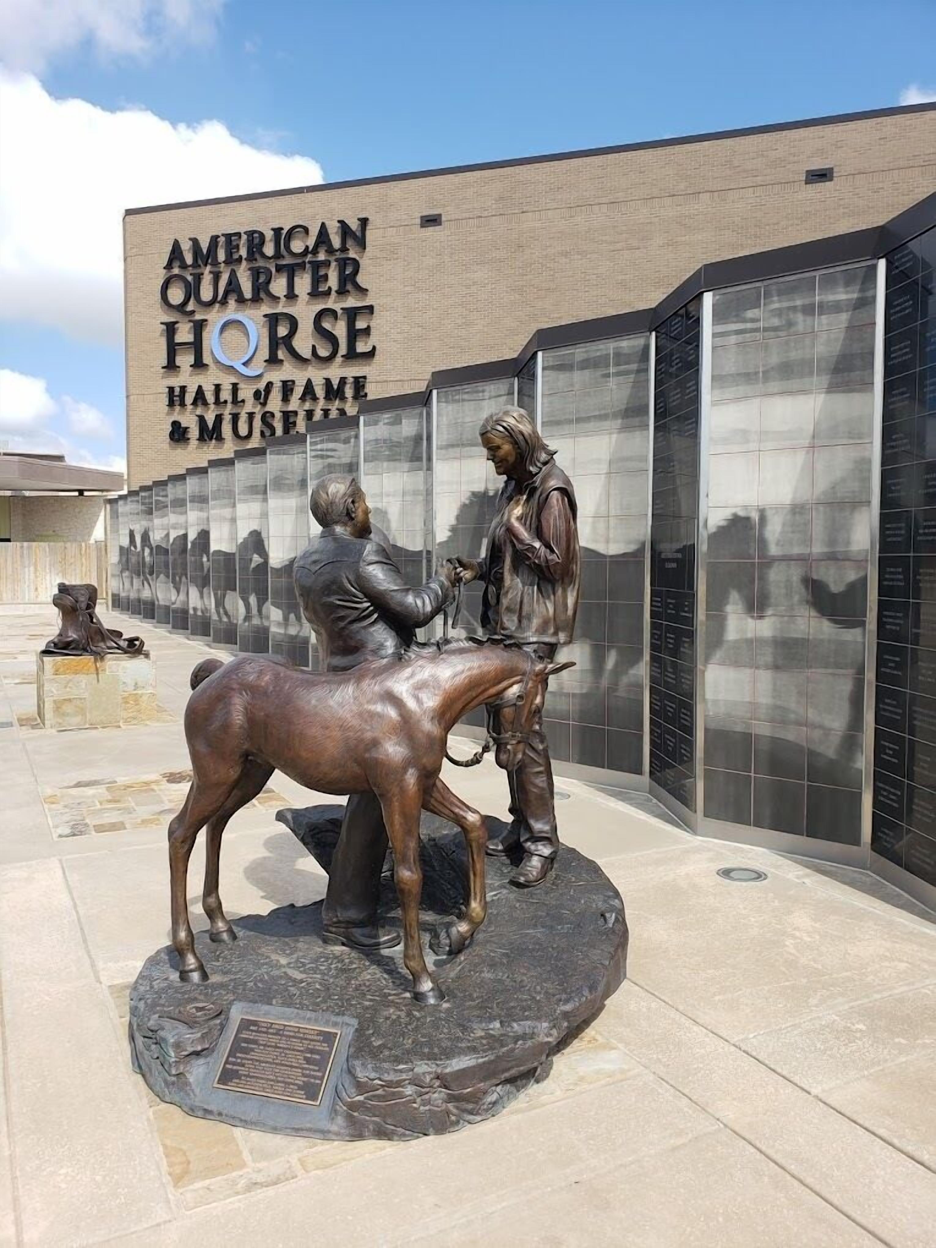 Een bronzen beeld van een man en vrouw met een paard voor het American Quarter Horse Hall & Museum.
