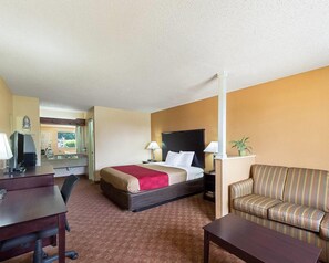 A hotel room with a bed, a desk, a chair, a sofa, and a mirror. - Econo Lodge Inn & Suites San Antonio near Frost Bank Center (San Antonio)