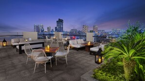 Une terrasse sur le toit avec des sièges extérieurs, une vue panoramique sur la ville et un jardin bien entretenu.