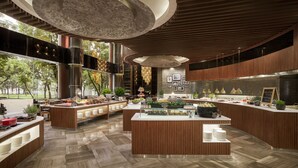 Um restaurante moderno com detalhes em madeira, uma ilha central com expositores de comida e vista para o exterior.
