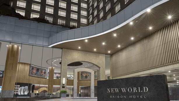 L’extérieur du New World Saigon Hotel présente un design moderne, avec une façade incurvée, de grandes fenêtres et une enseigne d’entrée bien visible.