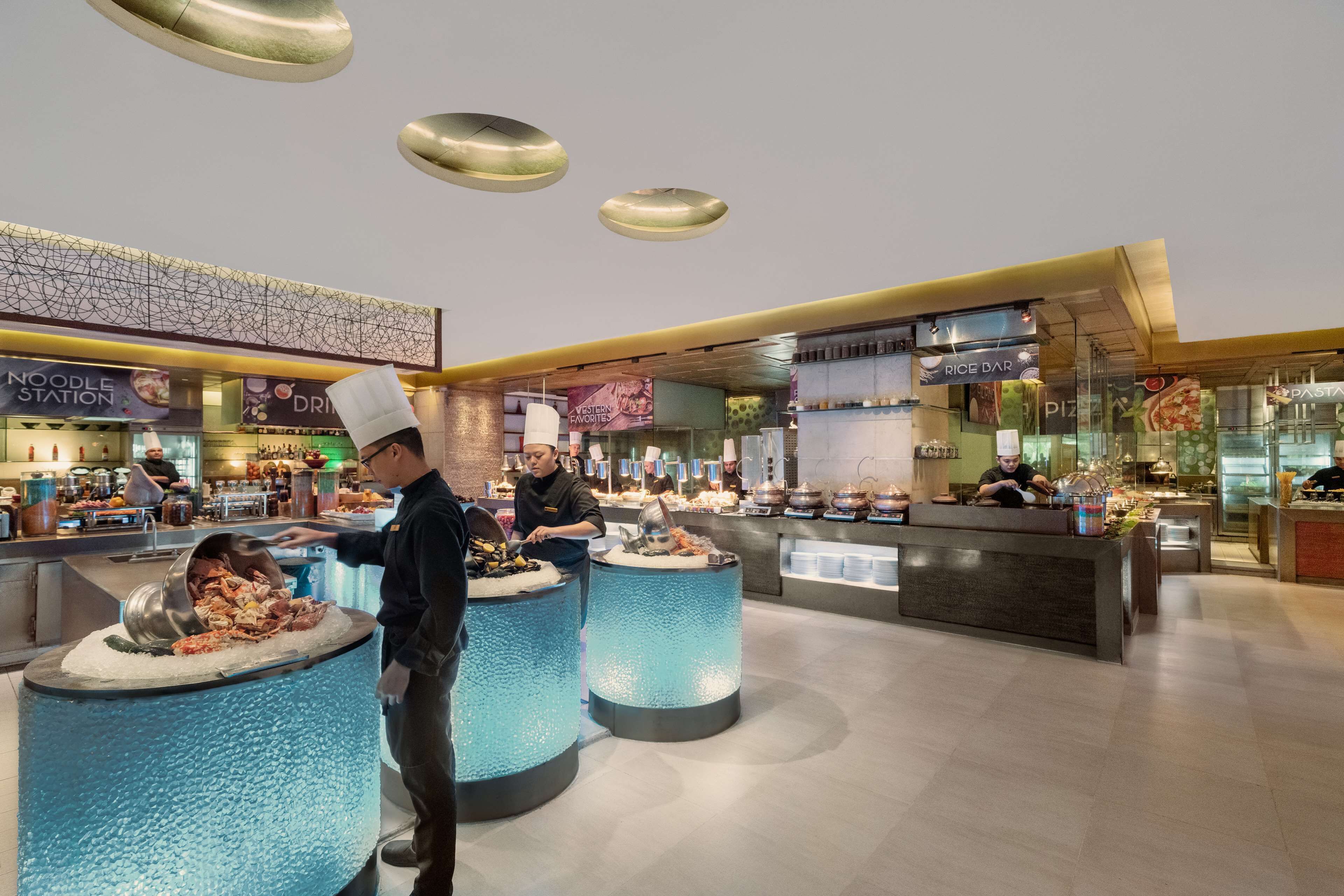 Zona de buffet con varias estaciones de comida, que incluyen una estación de fideos y una barra de arroz.
