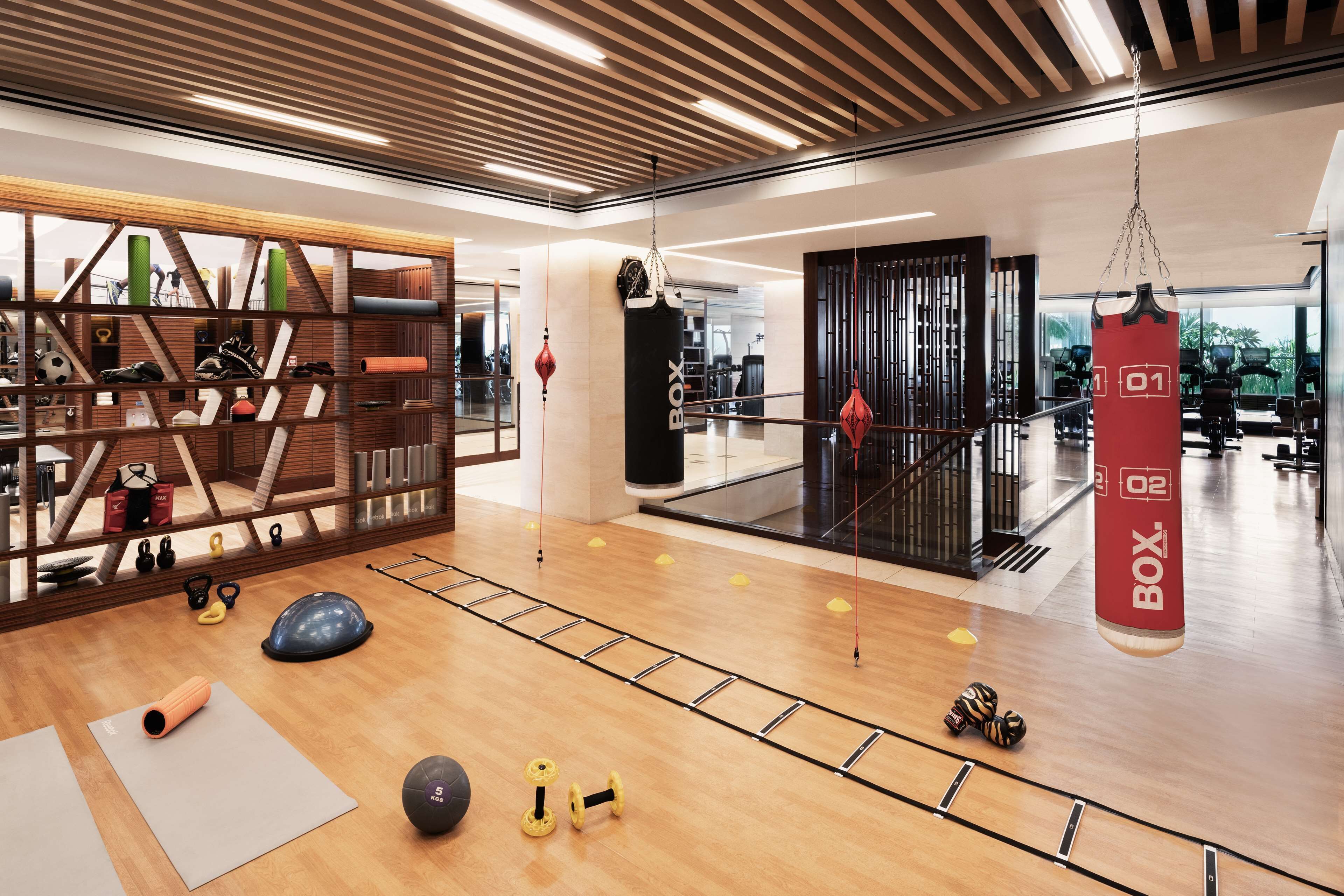 A modern gym with wooden flooring, exercise equipment, and a punching bag.