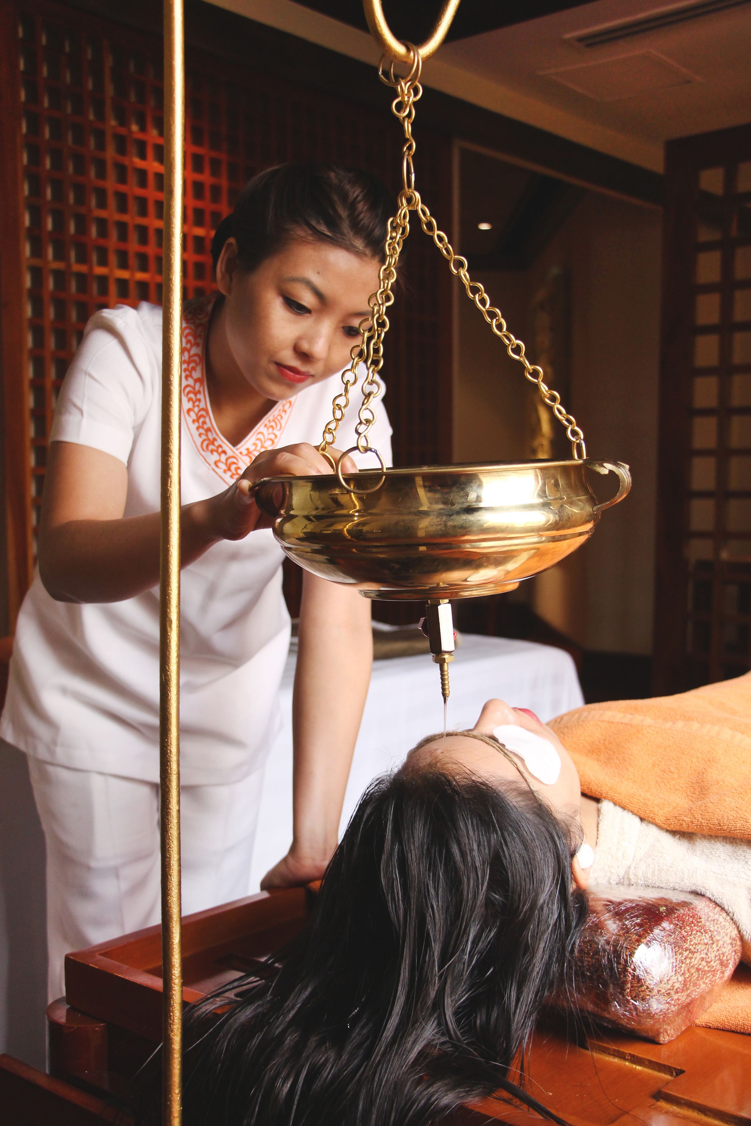 A person receiving a traditional massage with a metal bowl and a massage oil bottle.