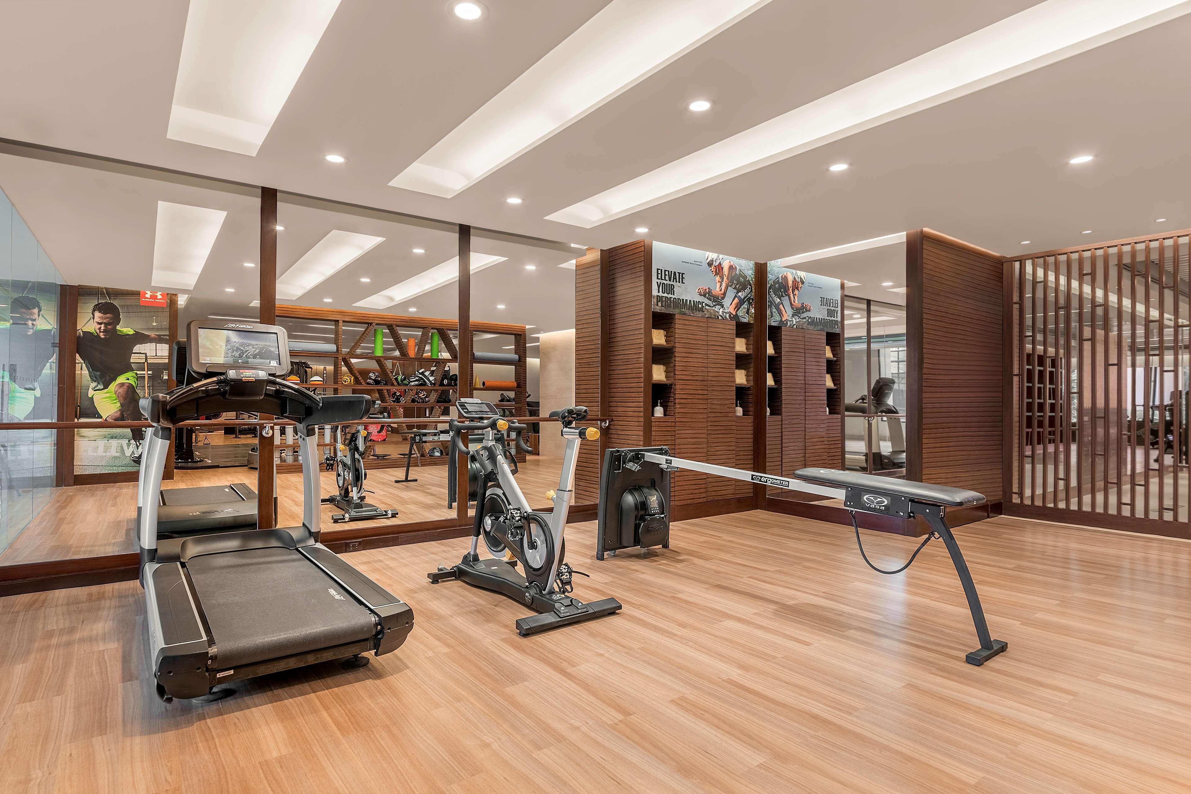 A modern gym with treadmills, stationary bikes, and a mirrored wall.