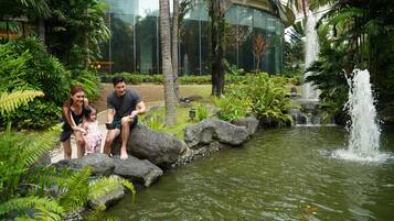 Una familia junto a un estanque rodeado de rocas y abundante vegetación.