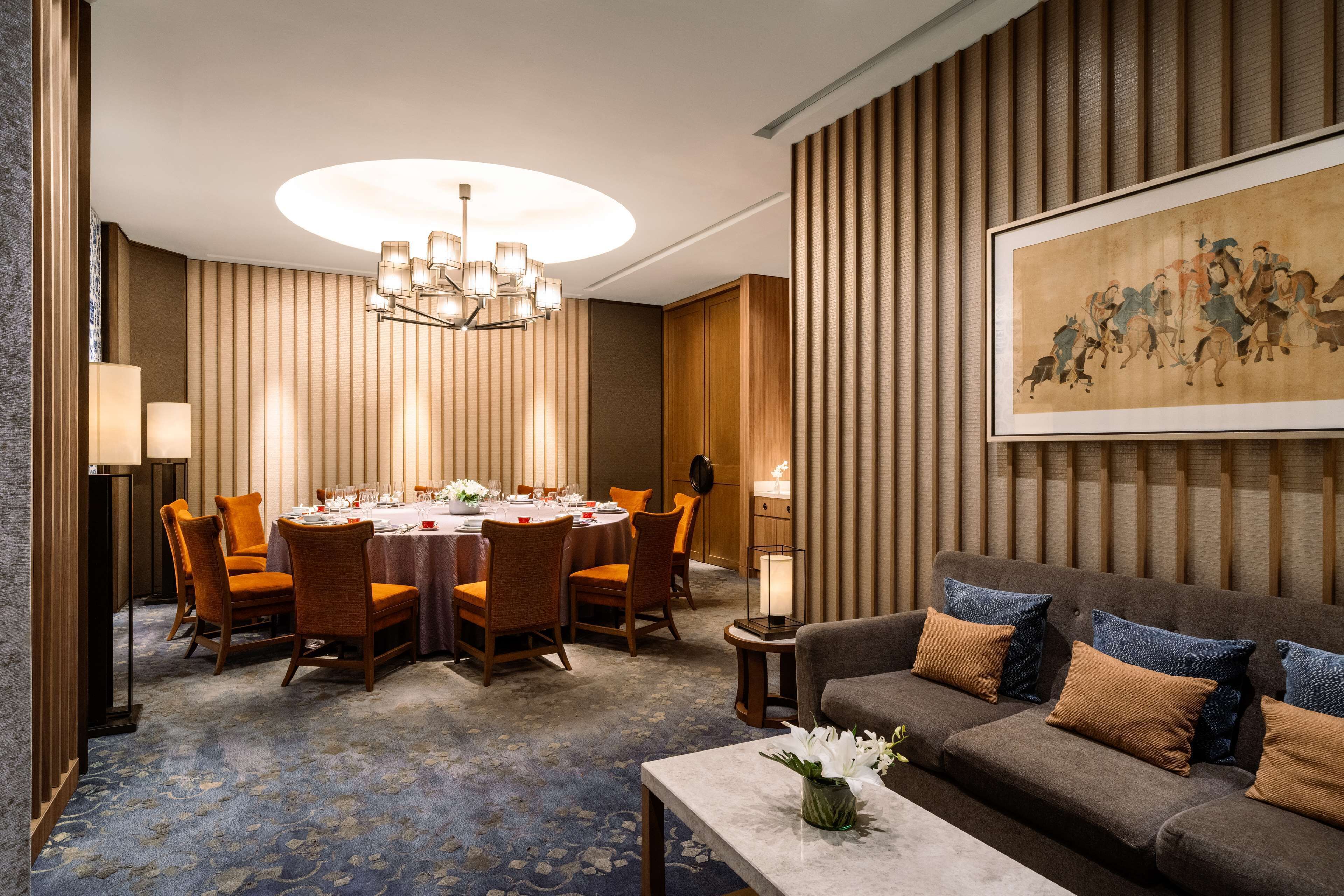 A dining area with a round table, chairs, and a chandelier.