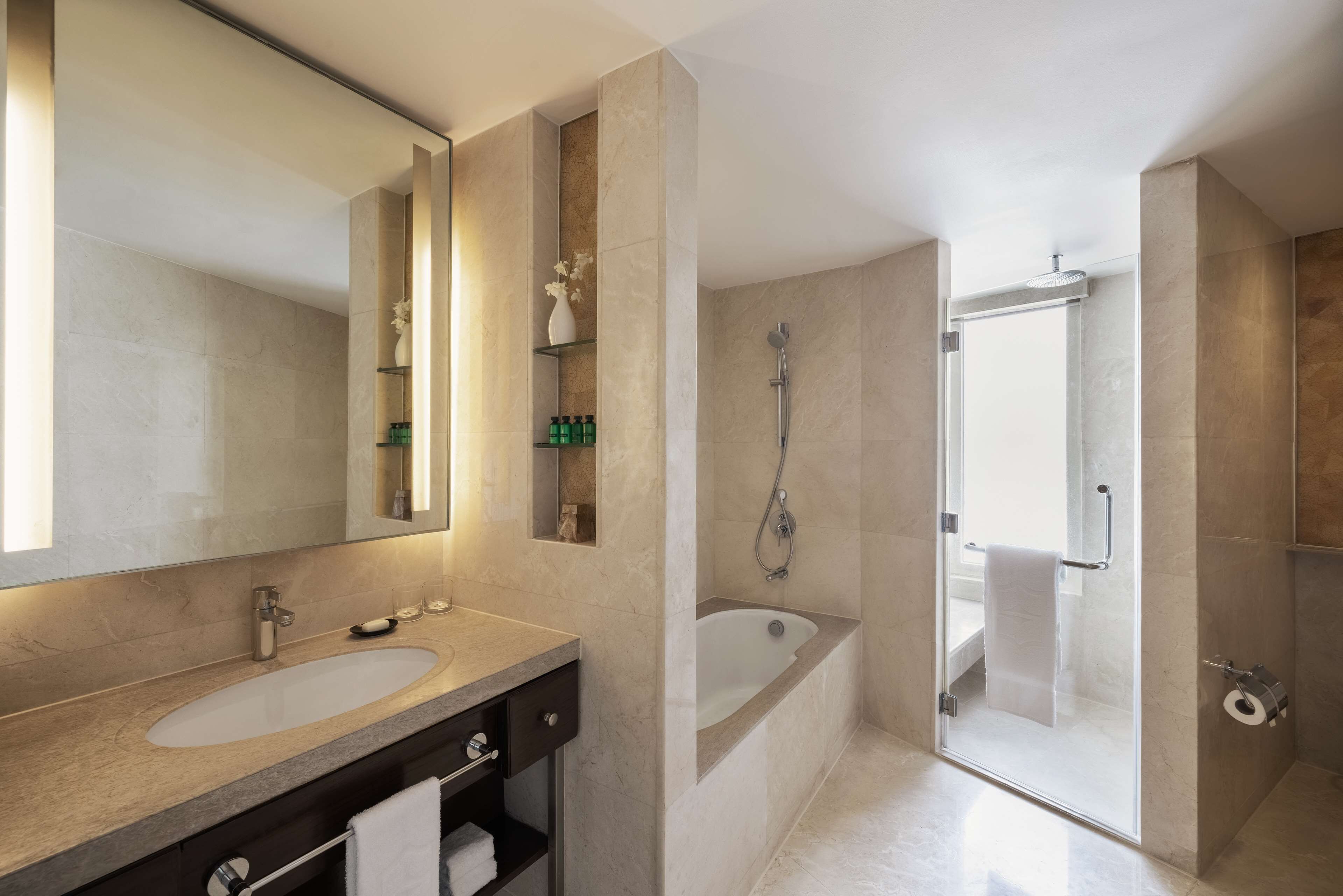 A modern bathroom with a large mirror, a sink, a bathtub, and a shower area.
