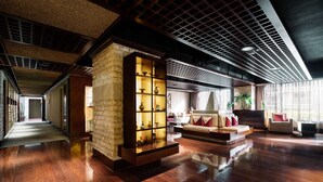Un hall d’entrée spacieux doté d’un plancher en bois, d’un mur décoratif en pierre et d’un coin salon avec un canapé et des fauteuils.