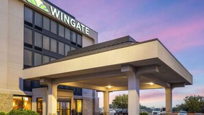 Un hôtel Wingate doté d’une entrée couverte, d’un espace extérieur aménagé et d’un parking.