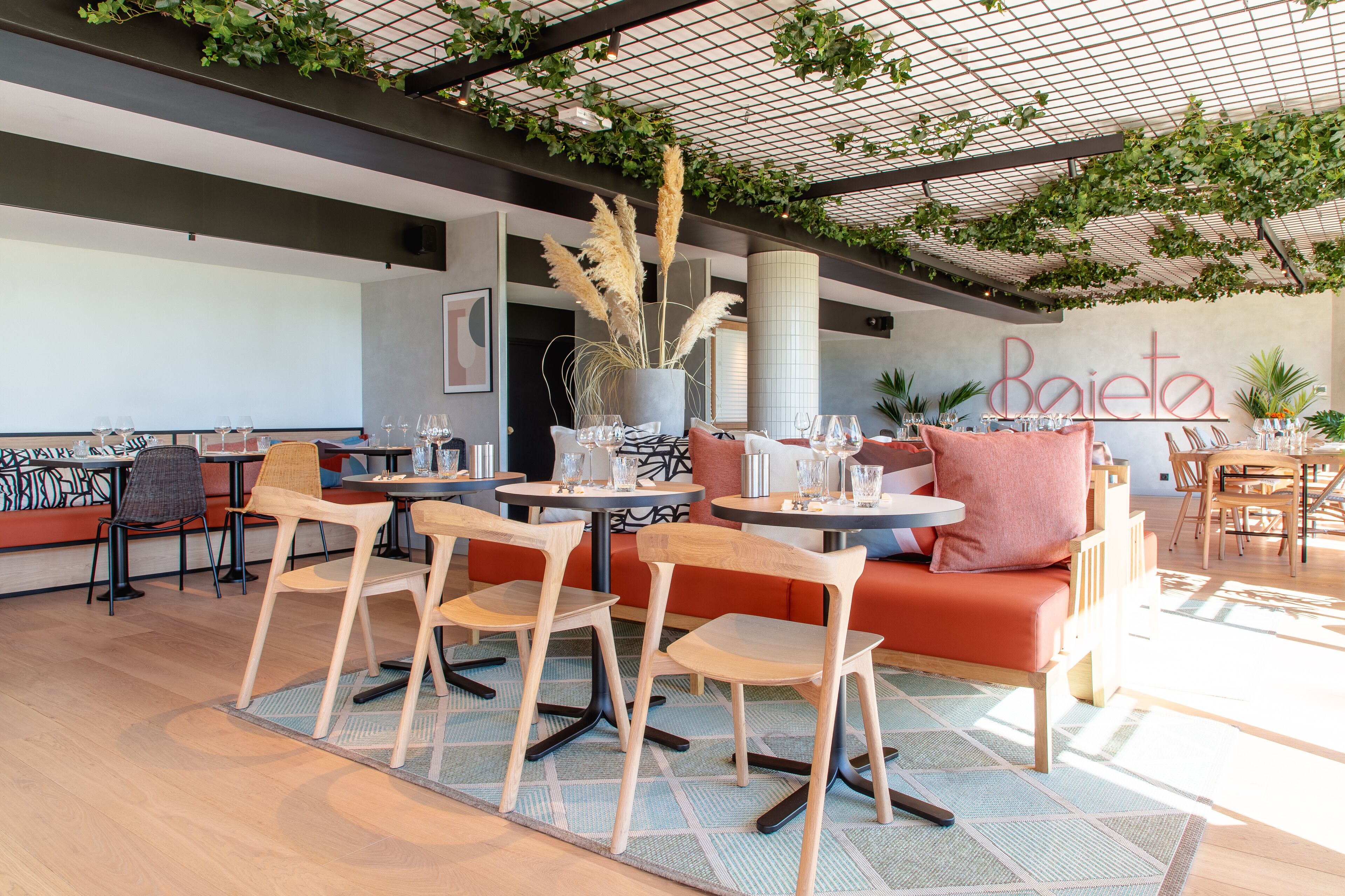 Ein moderner Essbereich mit Holztischen und -stühlen, einem roten Sofa und einem Dachgarten.