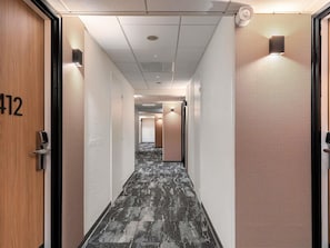 A hotel hallway with a number 412 door, a patterned carpet, and a ceiling with recessed lighting. - ibis Nice Aéroport Promenade des Anglais (Nice)