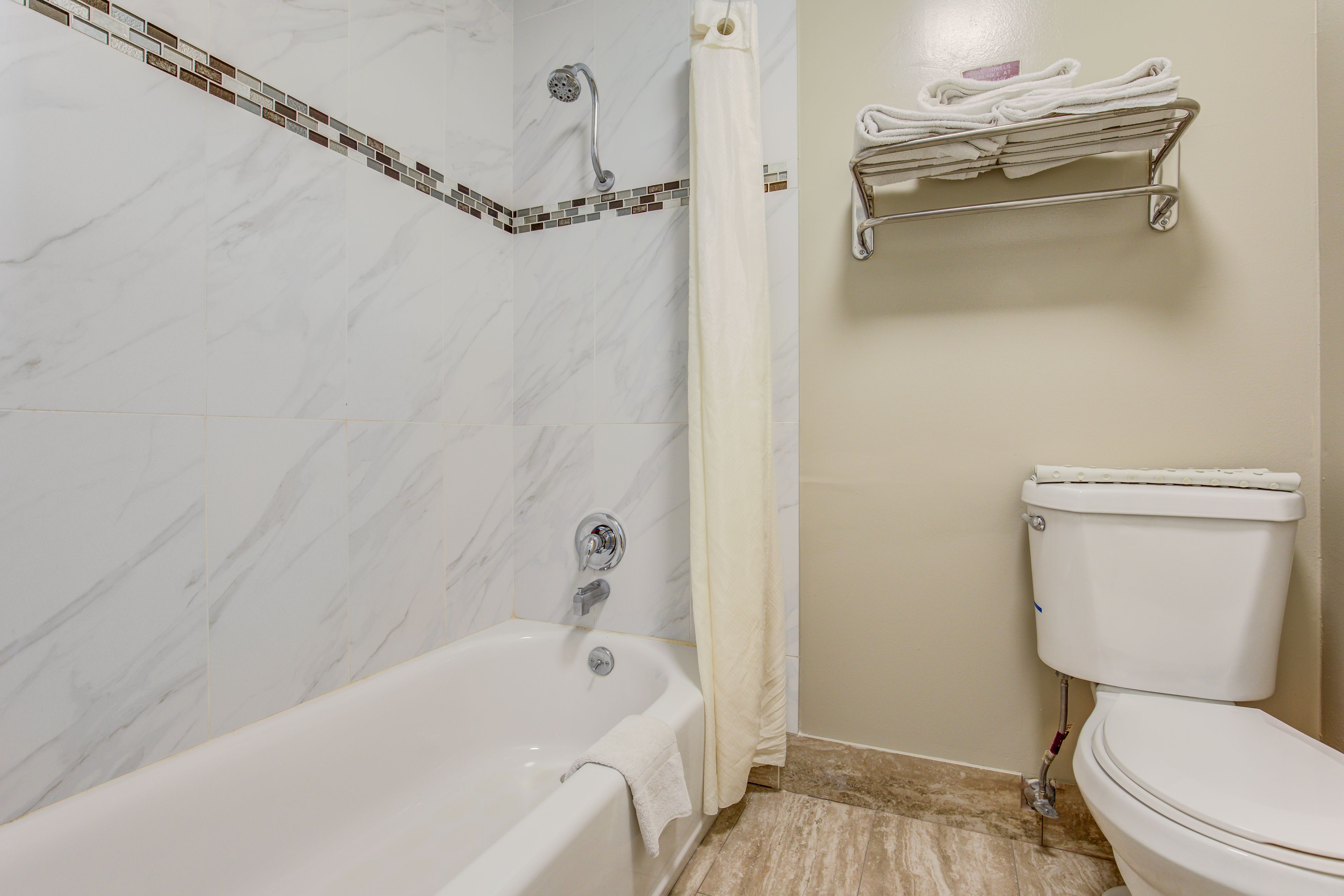 A bathroom with a bathtub, shower, toilet, and towel rack.
