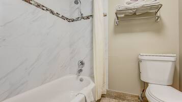 Un baño con bañera, ducha, inodoro y toallero.