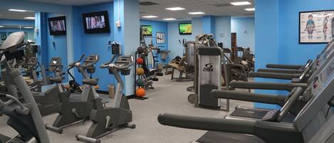 A gym with various exercise equipment, including treadmills, stationary bikes, and weight machines.