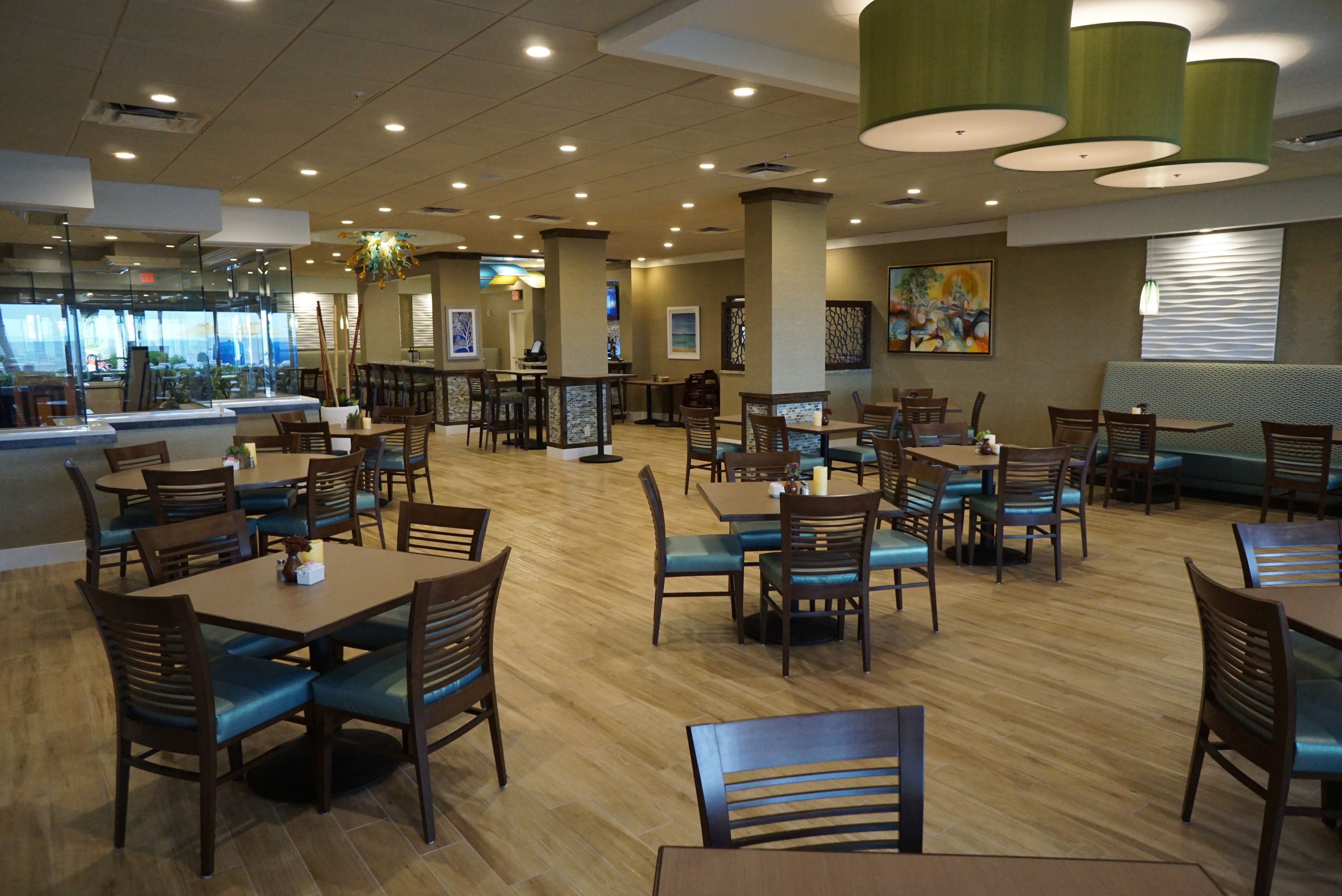 Ein geräumiges Restaurant mit Holztischen und -stühlen, einer Bar und Kunstwerken an den Wänden.