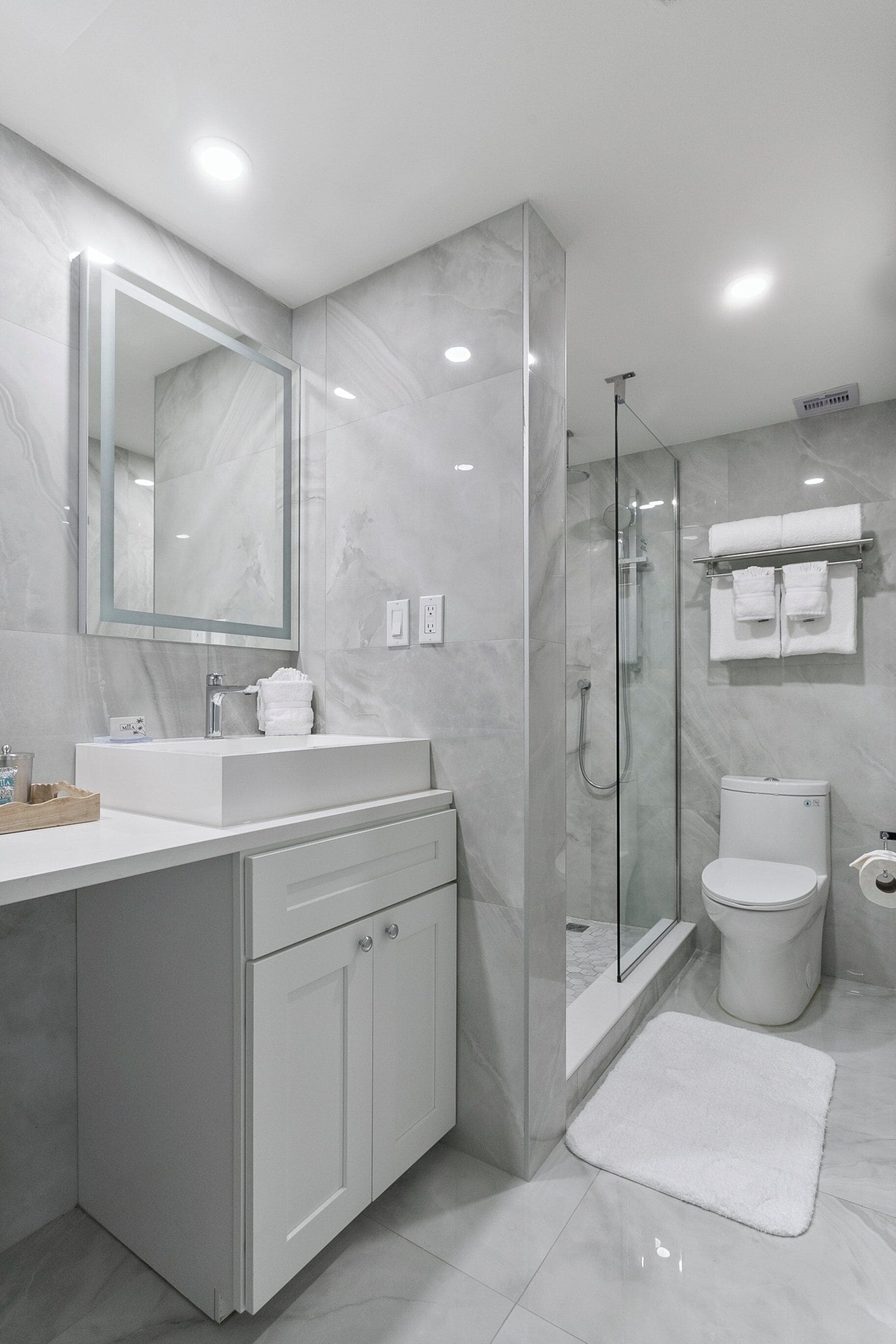 Een moderne badkamer met een douche met glazen wand, een wit wastafel en een grote spiegel.