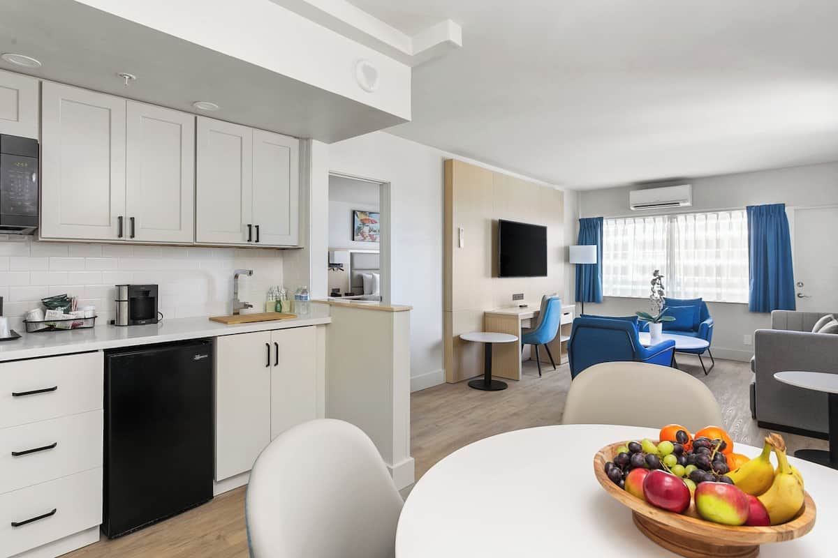 A modern kitchen with white cabinets, a black refrigerator, and a dining area with a table and chairs.