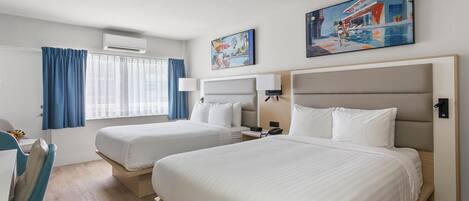 Habitación de hotel con dos camas, un escritorio y una silla.