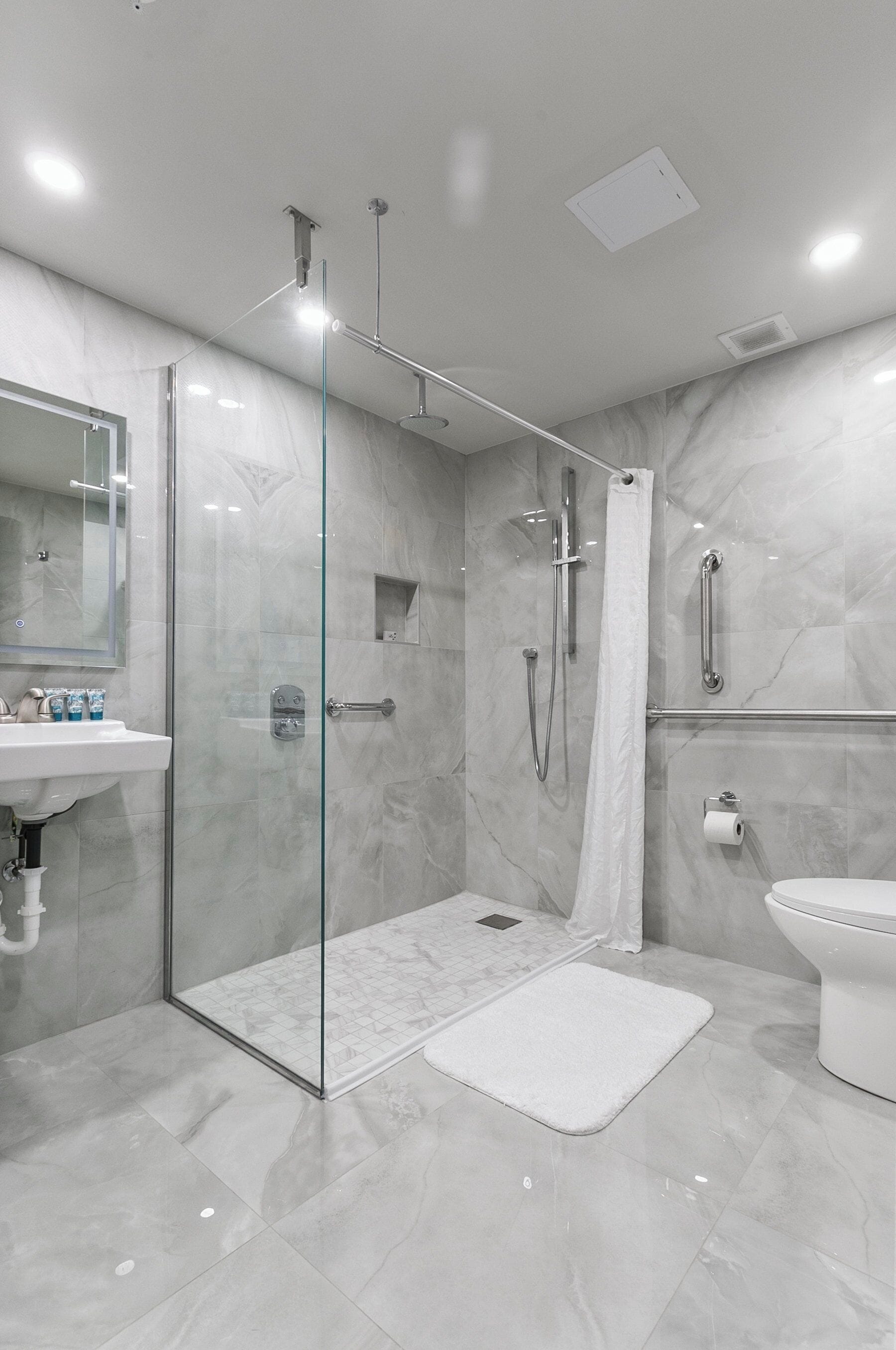 Een moderne badkamer met een douchecabine van glas, een witte wastafel en een toilet.