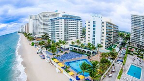 A hotel with a pool, beach, and ocean view.