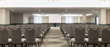 A conference room with rows of chairs, a patterned carpet, and a chandelier.