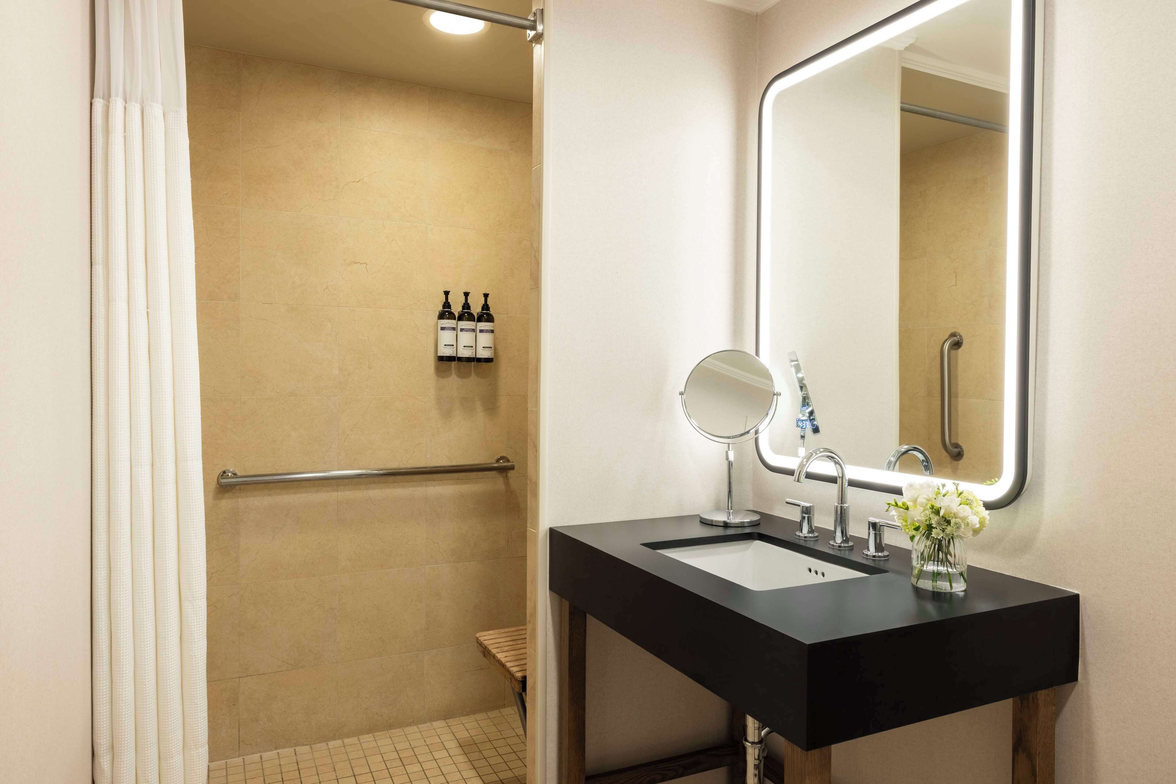 A modern bathroom with a black sink, a mirror, and a shower area.