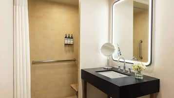 Un baño moderno con un lavabo negro, un espejo y una zona de ducha.