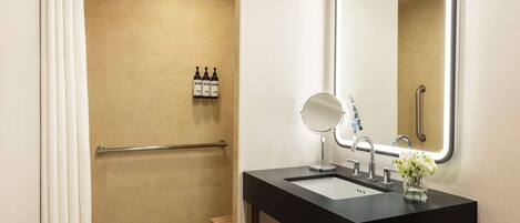 A modern bathroom with a black sink, a mirror, and a shower area.