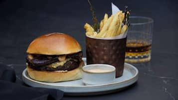 A burger with fries and a drink on a plate.