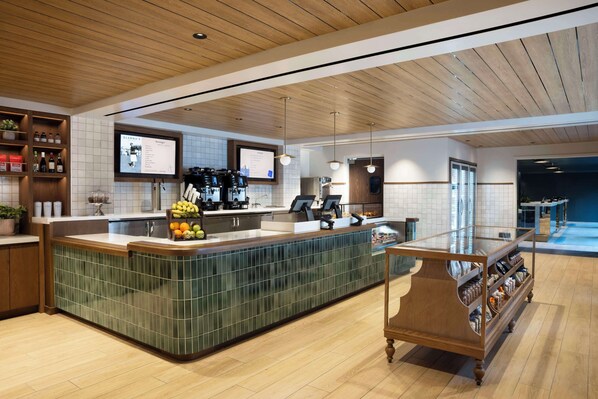 Una cocina moderna con una isla central, techo de madera y una cafetera.
