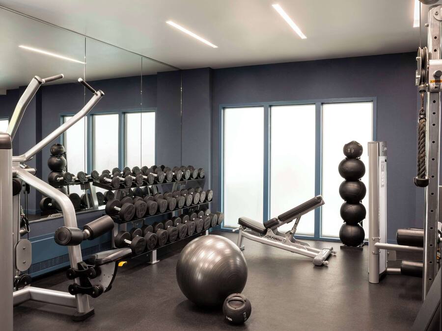 A gym with exercise equipment, dumbbells, and exercise balls.