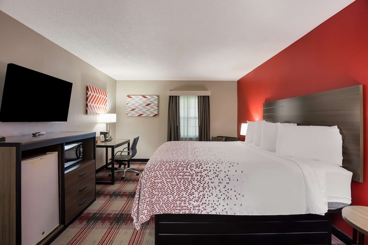 A hotel room with a bed, desk, and TV.