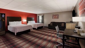 A hotel room with two beds, a desk, a sofa, a TV, and a window with curtains. - SureStay Hotel by Best Western Higginsville (Higginsville)