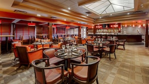 Un restaurante espacioso con varias mesas y sillas, una zona de bar y un diseño de techo moderno.