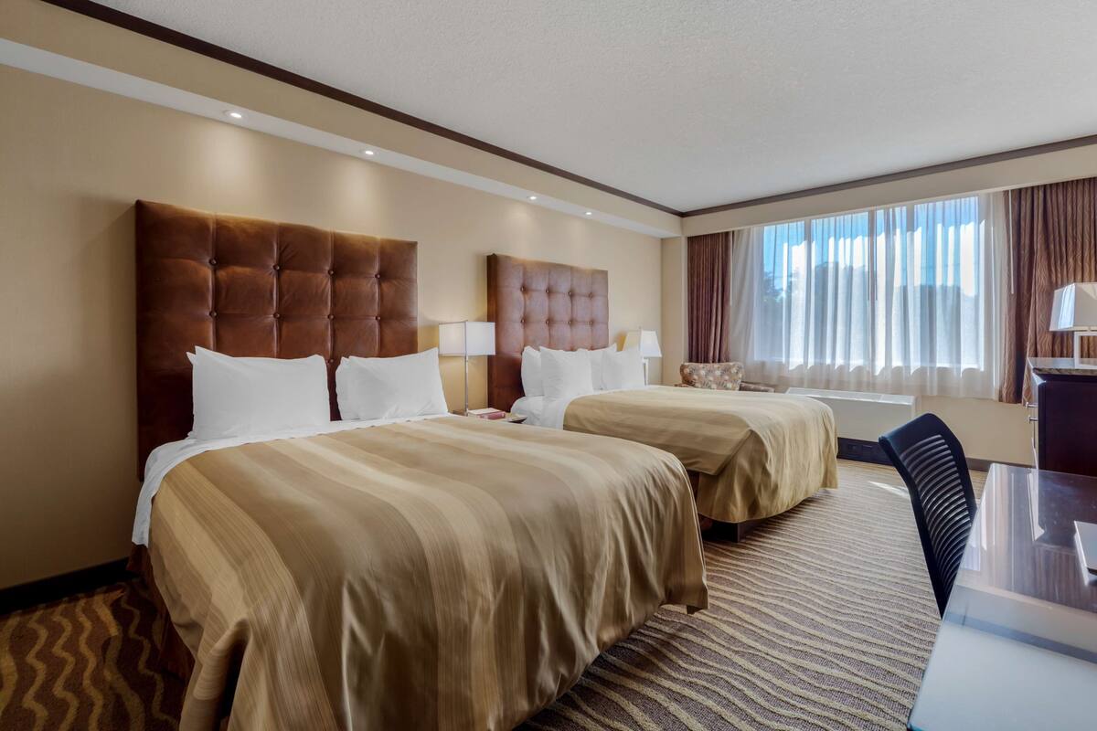 Ein Hotelzimmer mit zwei Betten, einem Schreibtisch und einem Stuhl.