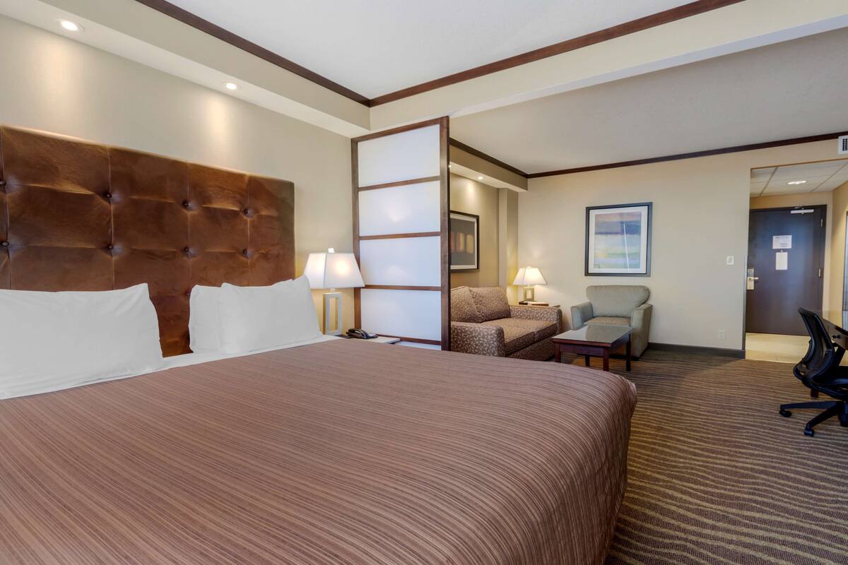 Ein Hotelzimmer mit einem großen Bett, zwei Stühlen, einem Schreibtisch und einem Sofa.