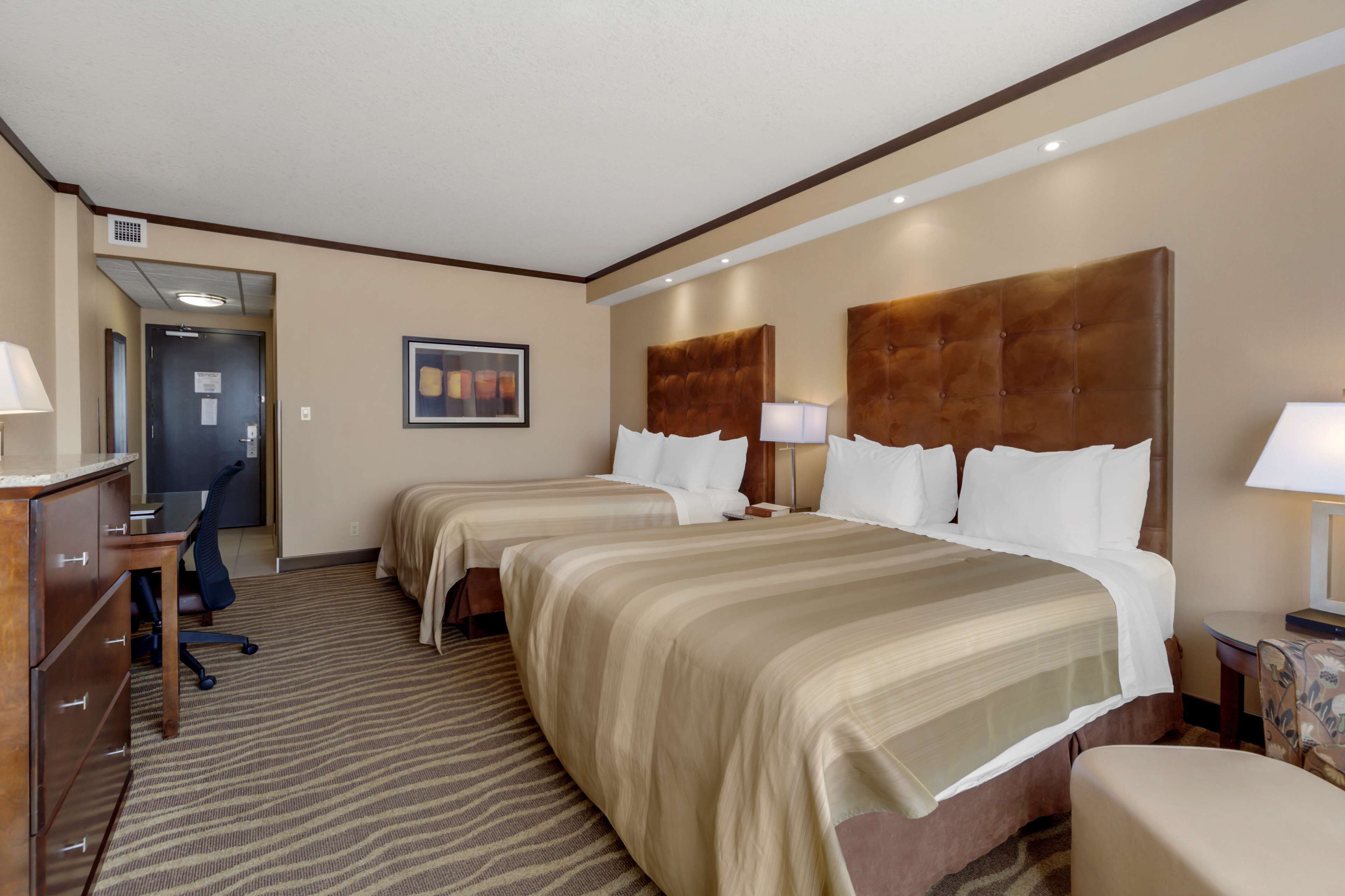 Habitación de hotel con dos camas, un escritorio y una silla.