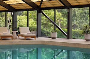 A pool area with two lounge chairs and potted plants.