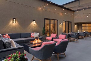 An outdoor seating area with a fire feature, lounge chairs, and ambient lighting.