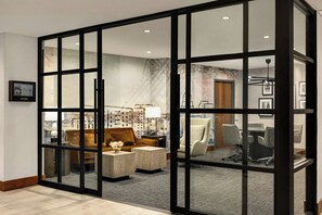 A hotel room with a glass partition, a sofa, a coffee table, and a desk with chairs. - Madison Marriott South (Madison)