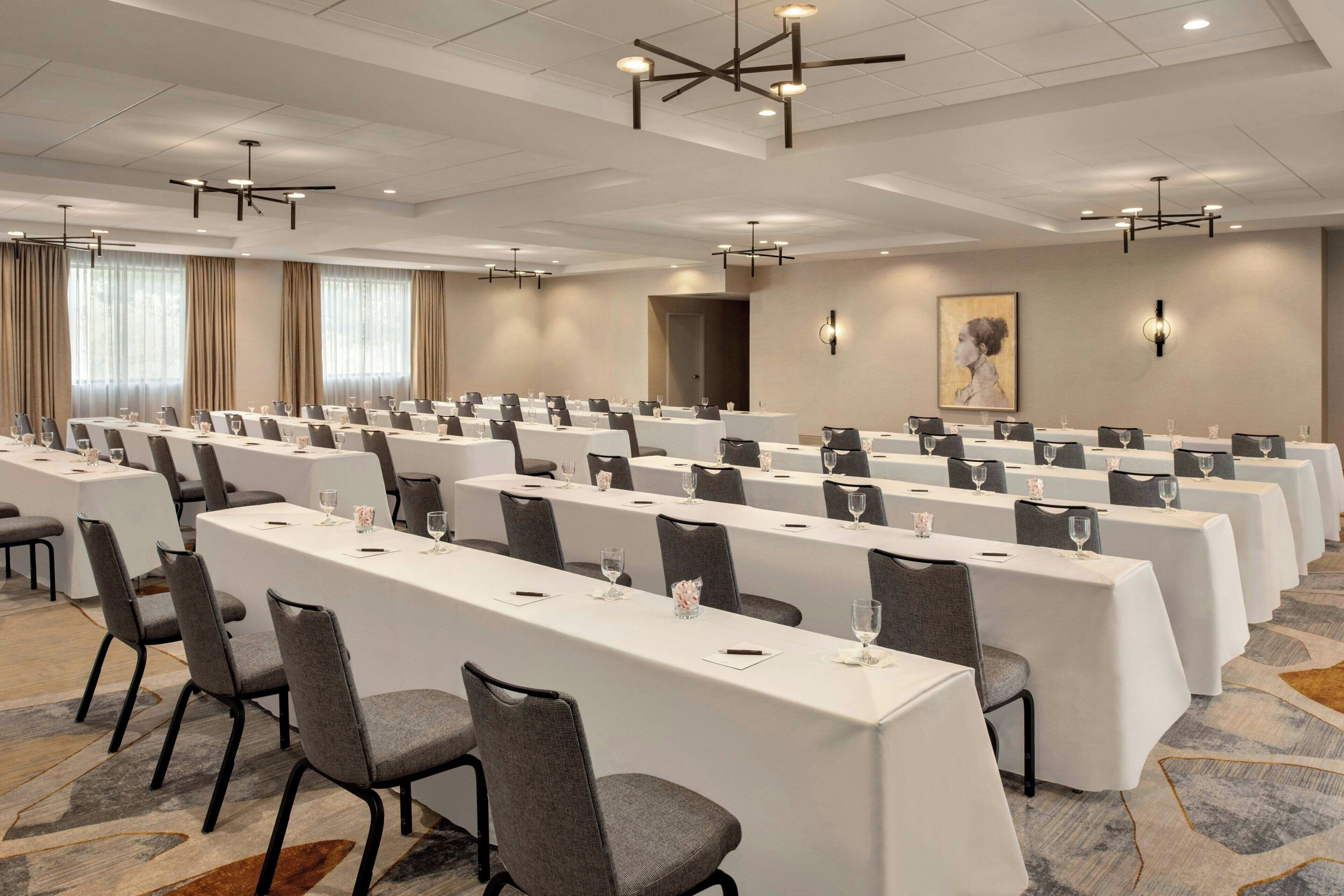 A conference room with long tables, chairs, and modern lighting fixtures.