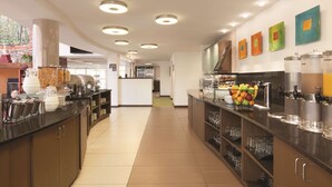 A modern kitchen with a long counter, various food dispensers, and a fruit bowl. - Homewood Suites by Hilton Harrisburg-West Hershey Area (Mechanicsburg)