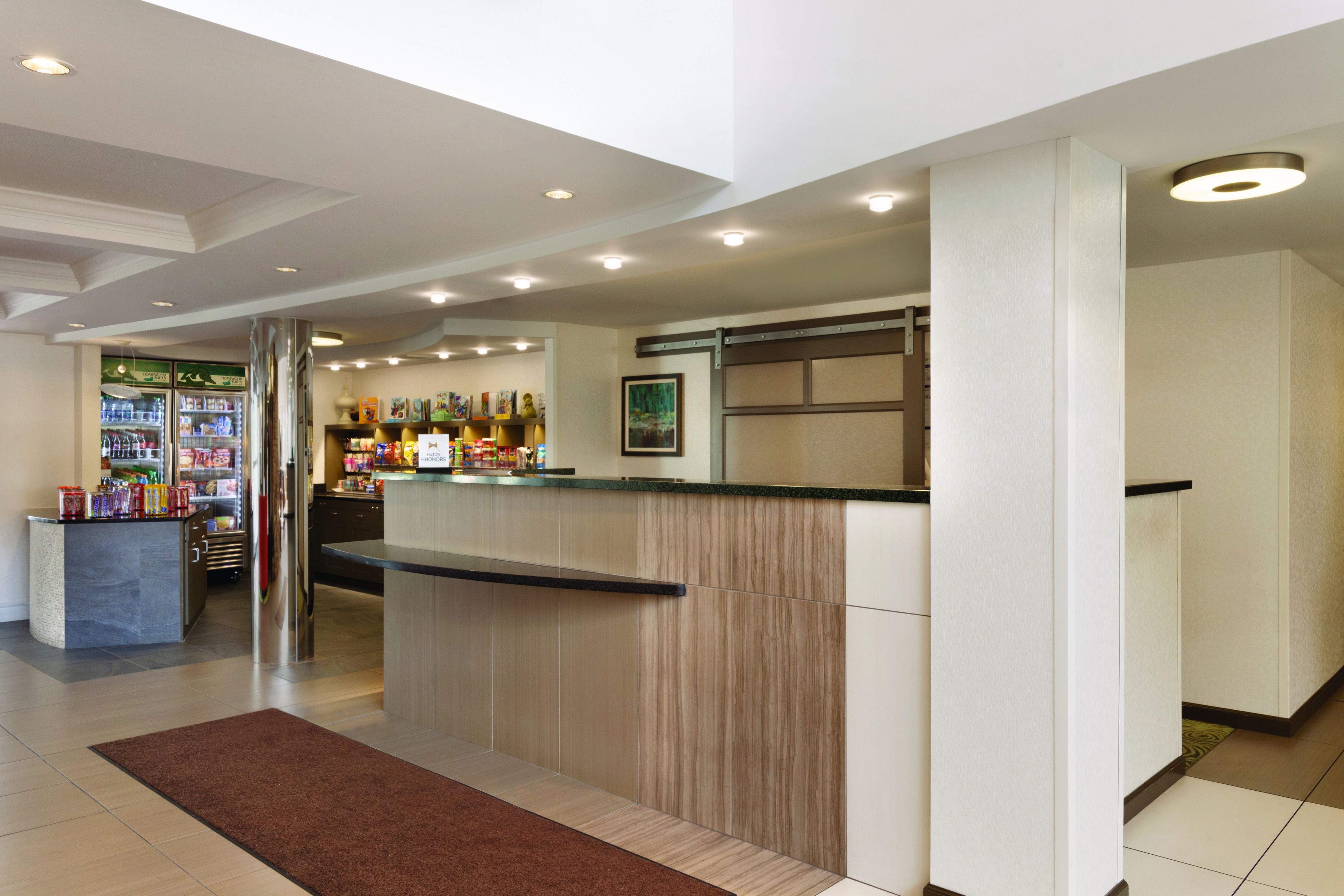 A hotel reception area with a counter, a refrigerator, and a display of various items.